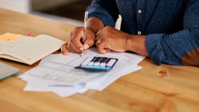 Cropped shot of an unrecognizable mature man calculating and going over his finances at home.