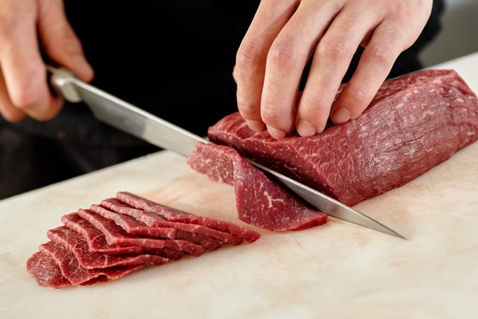 Japanese man slicing meat.