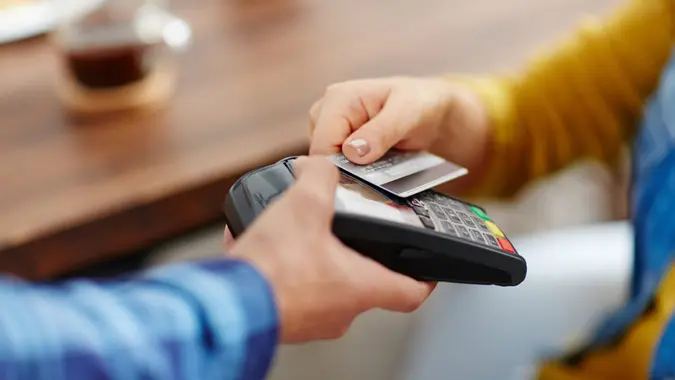 Close-up of unrecognizable customer choosing contactless payment using credit card while waitress accepting payment over nfc technology.