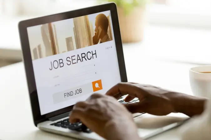 African man browsing work opportunities online using job search computer app, black jobless seeker looking for new vacancies on website page at laptop screen, recruitment concept, rear close up view.