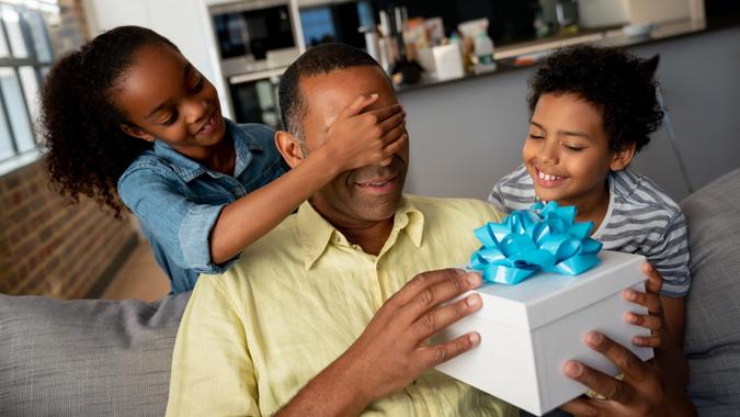 Kids surprising their father with a gift for Father's Day stock photo
