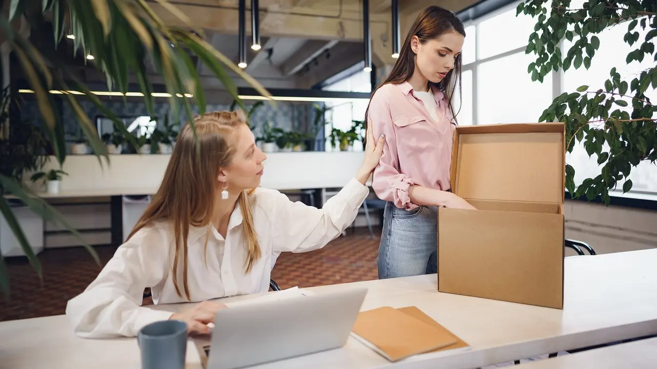 Young businesswoman holding box of personal belongings about to leave office after quitting job stock photo