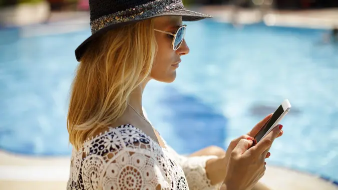 Attractive woman texting by the swimming pool stock photo