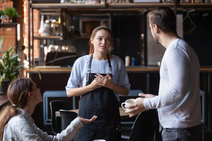Hostile angry restaurant client couple or friends talking with waiting staff in public place complains about cold coffee long service, spoiled tasteless dish waitress feels guilty mixed orders concept.