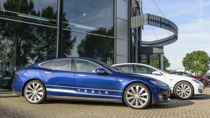 Blue and white Tesla Model S full electric luxury car parked outside a dealership.