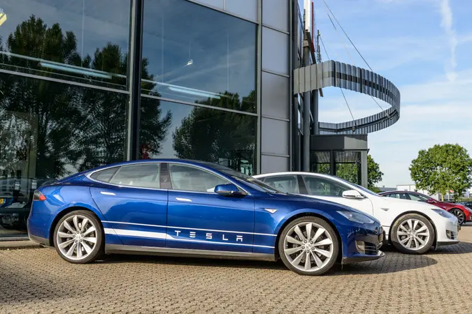 Blue and white Tesla Model S full electric luxury car parked outside a dealership.