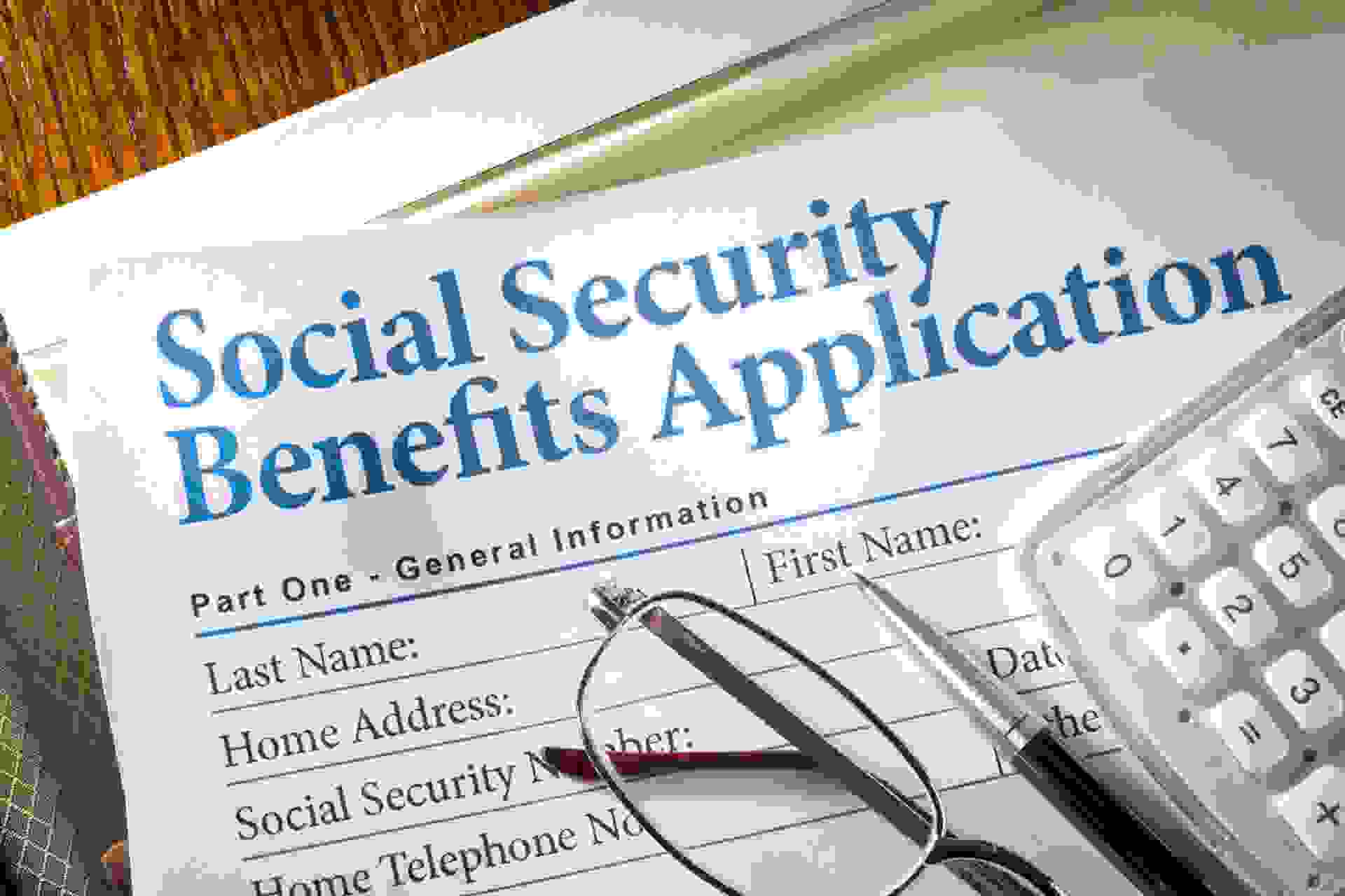 Social Security Benefits form with pen, glasses, and calculator.