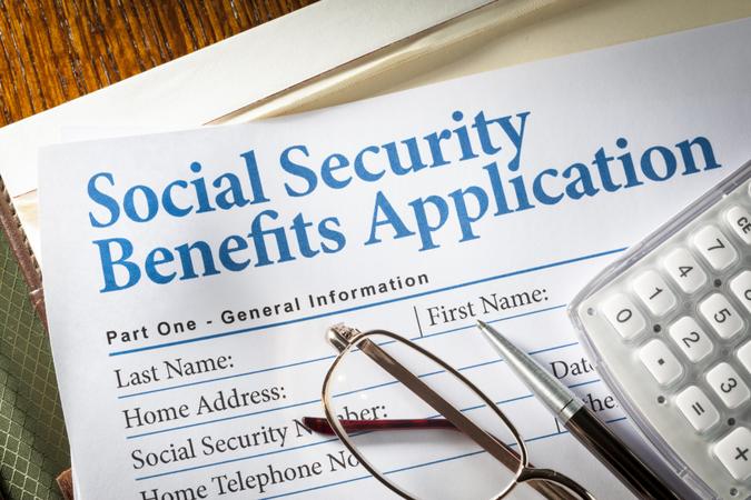 Social Security Benefits form with pen, glasses, and calculator.