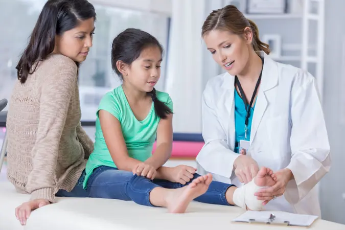 Emergency room doctor talks with young girl and the girl's mom about the girl's injured ankle.