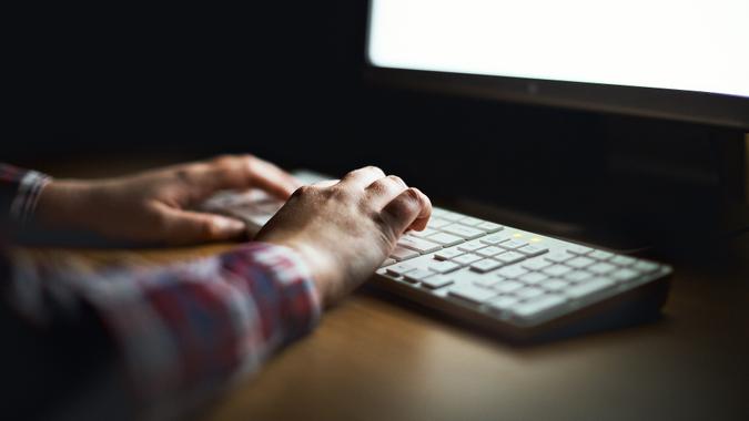 male hands typing at computer monitor_iStock-912422616 Hands type on computer keyboard lit by monitor stock photo