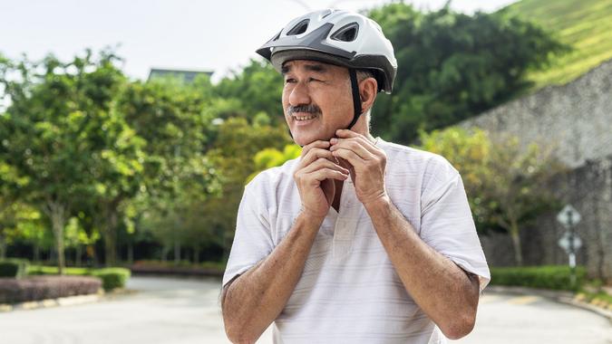 Senior Asian Man Adjusting Cycling Helmet In the City street stock photo