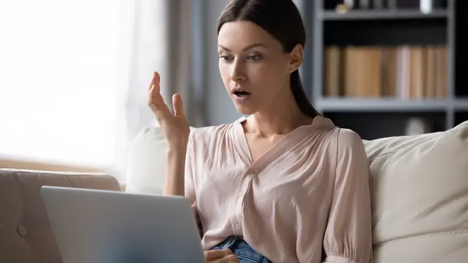 Shocked young woman looking at laptop screen, unexpected news stock photo