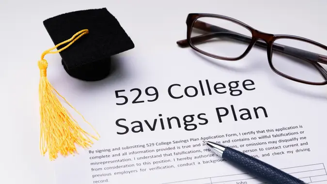 529 College Savings Plan Form With Small Graduation Hat, Spectacles And Pen Over White Background.