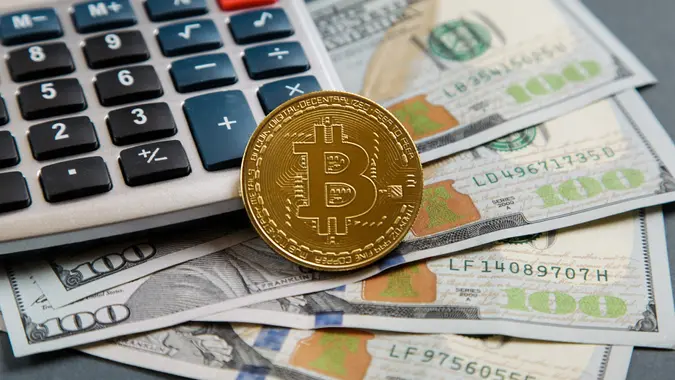 Kiev, Ukraine - May 16, 2021: Gold bitcoin coin, dollar bill Black electronic calculator. Crypto Investing cryptocurrency exchange money. Bitcoin to USD. Close up stock photo