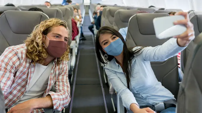 Friends traveling by plane wearing facemasks and taking a selfie stock photo