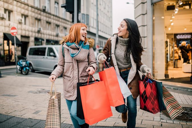 Happy two girls holding bunch of shopping bags.