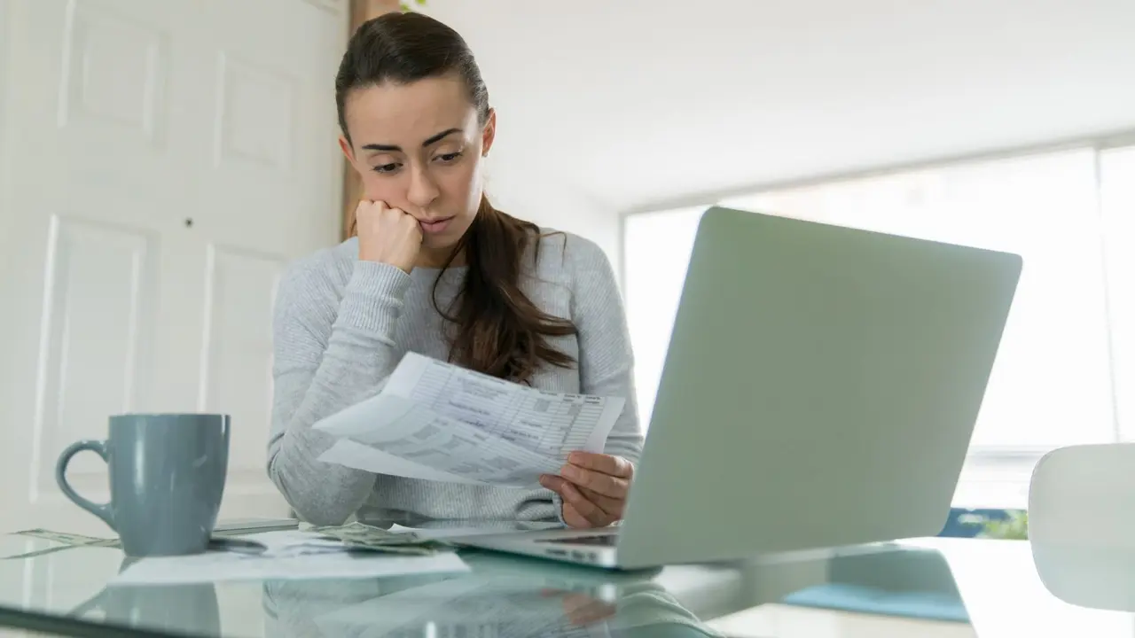 Woman paying her utility bills online and looking worried while staying at home during the pandemic - home finances concepts.
