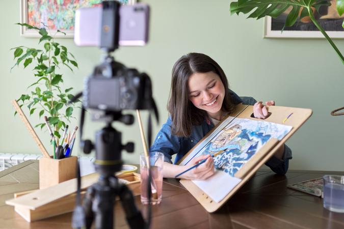 Artist, teenage girl, draws records on video camera for blog.