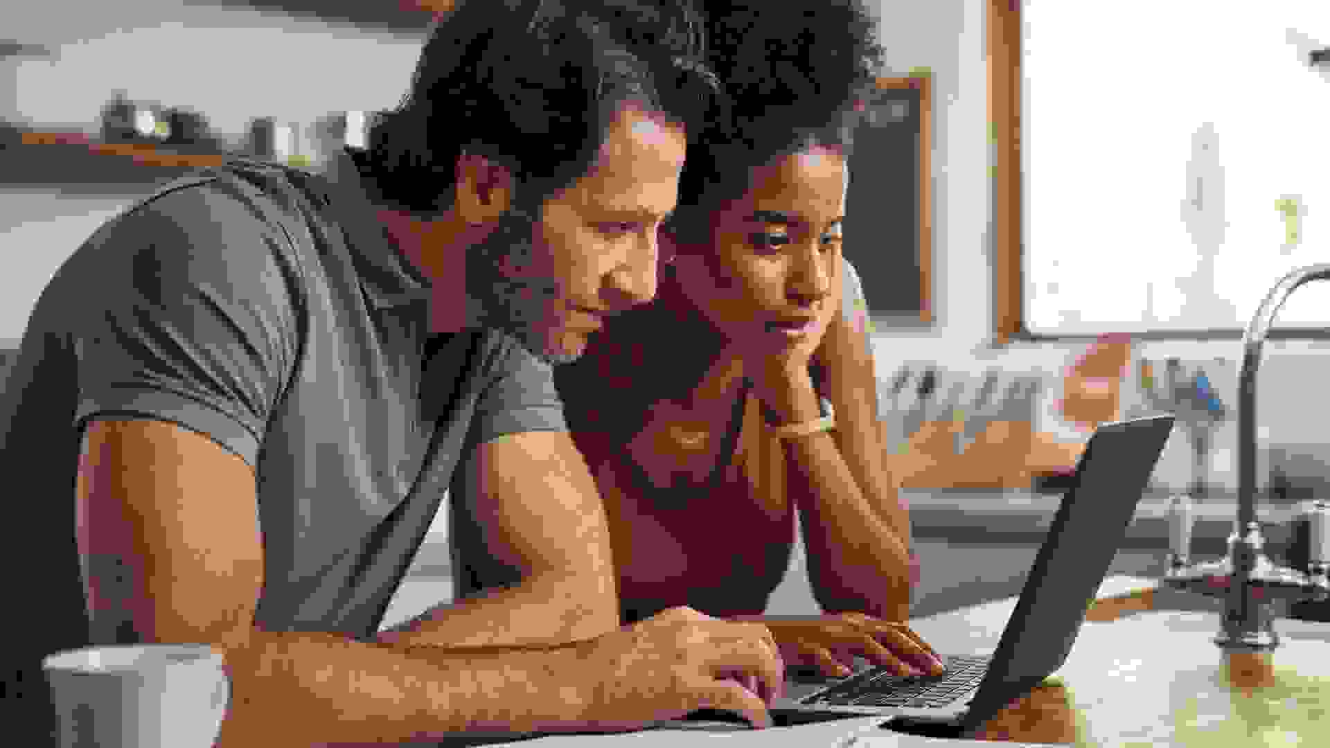 Cropped shot of a couple using their laptop and going through paperwork at home.