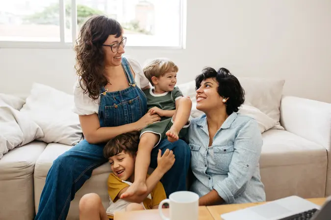 Happy lesbian couple playing with their children at home.