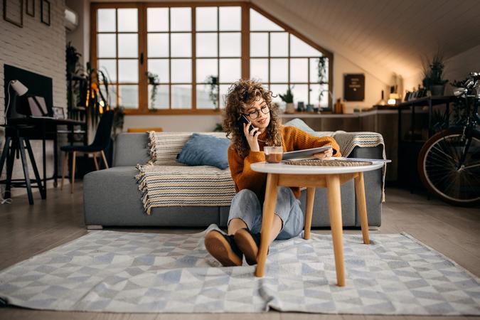 Young beautiful woman sitting on a floor and talking on a mobile phone.