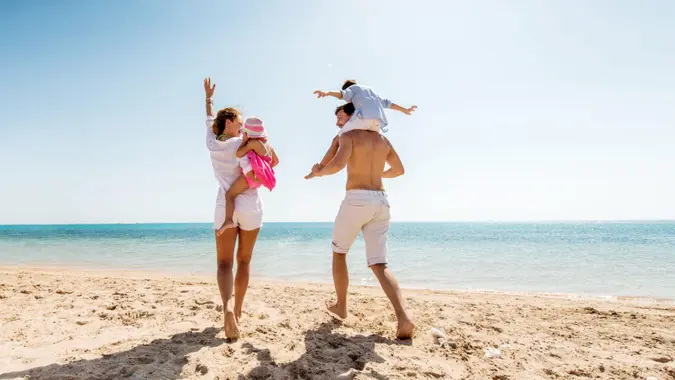 Cheerful parents enjoying at the beach with their little children.