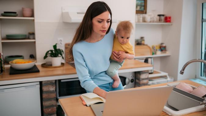 Young Caucasian mother working from home and taking care of her son stock photo