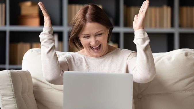 Excited middle-aged woman triumph reading good news on laptop stock photo