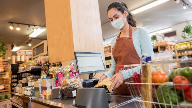 Cashier working at the supermarket wearing a facemask while scanning products stock photo