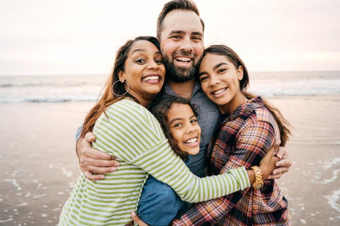 Smiling parents with two children on the beach.