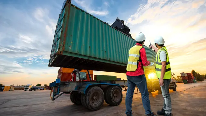 foreman working in container yars checking and report online by protable device.