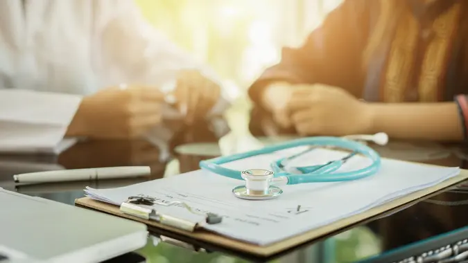 Stethoscope with clipboard and Laptop on desk,Doctor working in hospital writing a prescription, Healthcare and medical concept,test results in background,vintage color,selective focus.