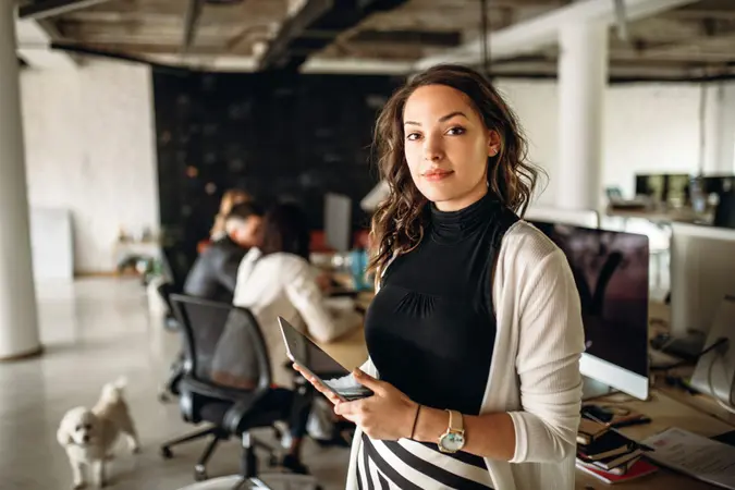 Portrait of a young business woman in the modern office, and a team behind her.