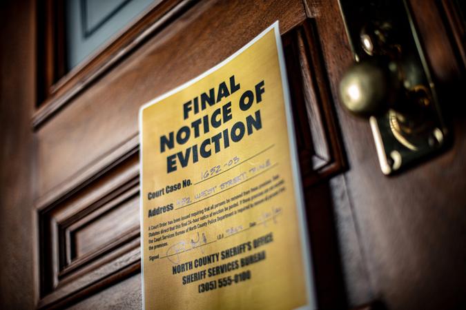 Eviction notice on door of house with brass door knob.