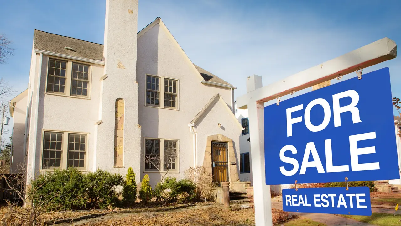 A classic Tudor style house in the mid-west of United States for sale with sale sign on lawn.