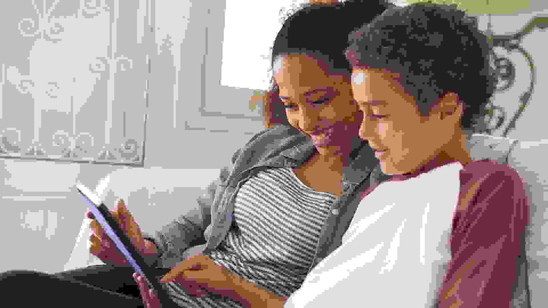 Mother And Son Sitting On Sofa Using Digital Tablet stock photo