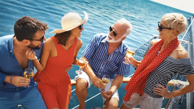 Closeup front view of a senior couple having some drinks with a younger couple they met on a sailing cruise.