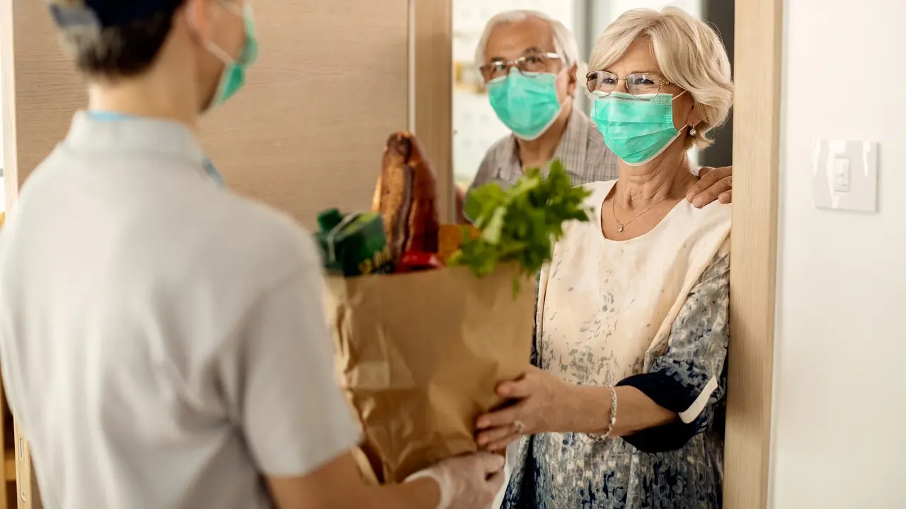 Happy mature woman and her husband receiving groceries at home during coronavirus epidemic. stock photo