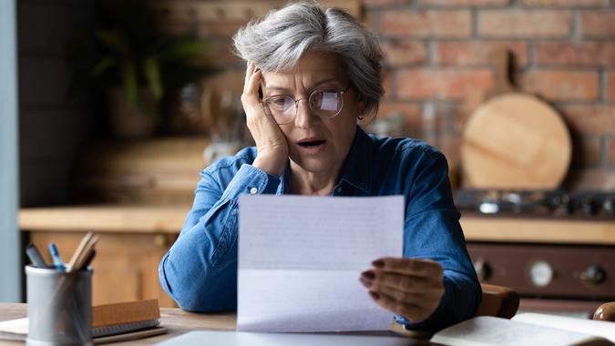 Unhappy mature wearing glasses reading bad news in letter stock photo