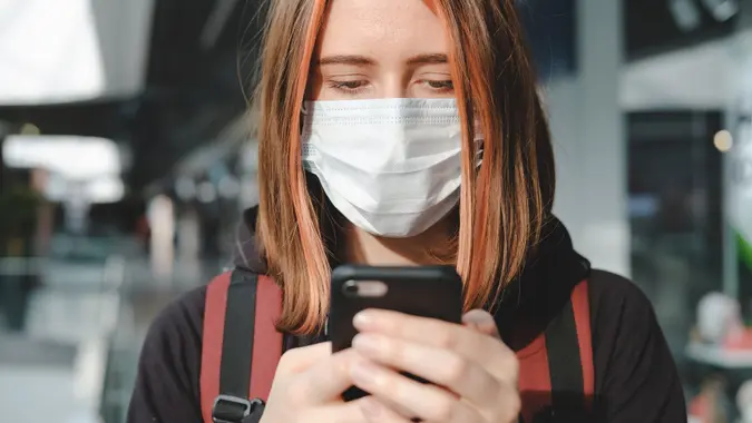 Woman in protective face mask using the phone at a public place. stock photo