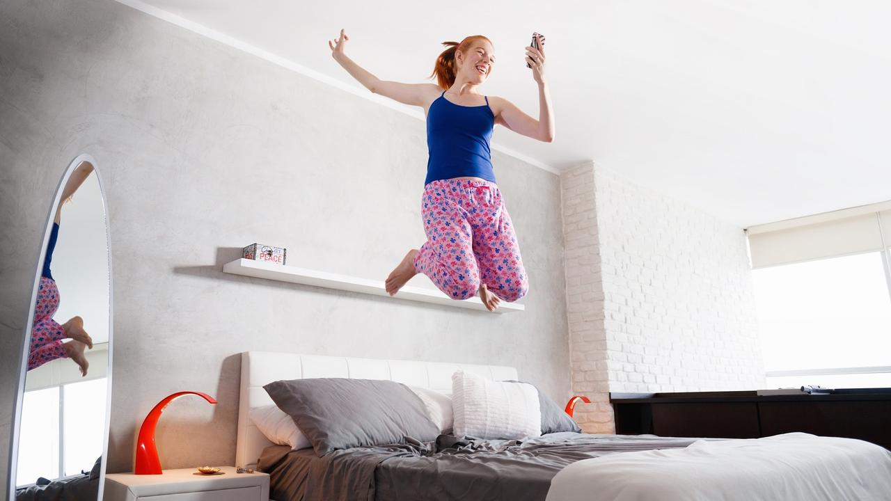 Good News For Happy Young Woman Girl Jumping On Bed stock photo