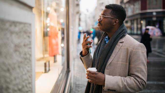 Side view of a young African American man in front of a store window stock photo