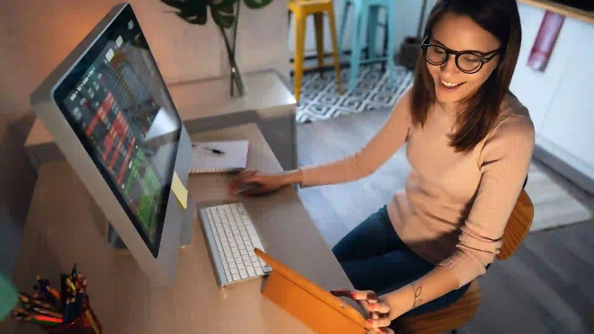High-angle view of a young woman trading cryptocurrency on a computer and digital tablet stock photo
