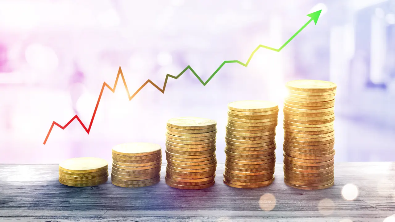 Five stacks of coins growing from left to right with a graph line above them, also growing.