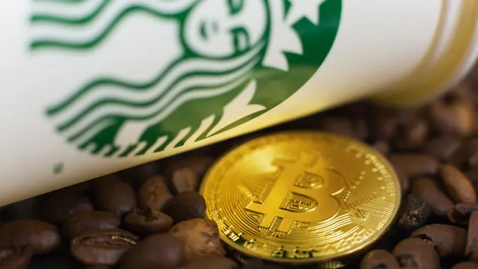 Cryptocurrency Bitcoin coin on coffee beans with Starbucks cup.