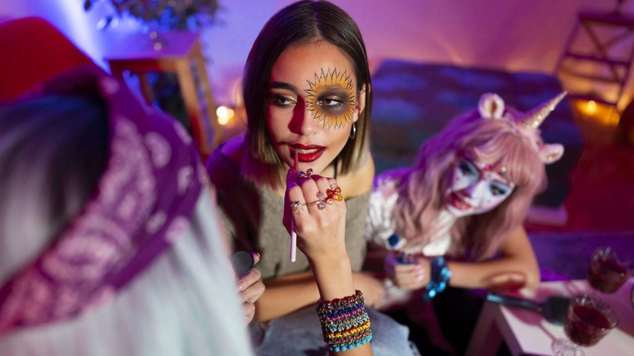 Girls preparing for Halloween party, doing make-up at home before going out.
