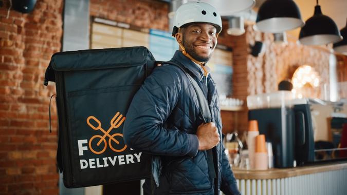 Handsome Black African American Food Delivery Courier Posing in Front of the Camera in a Coffee Shop.