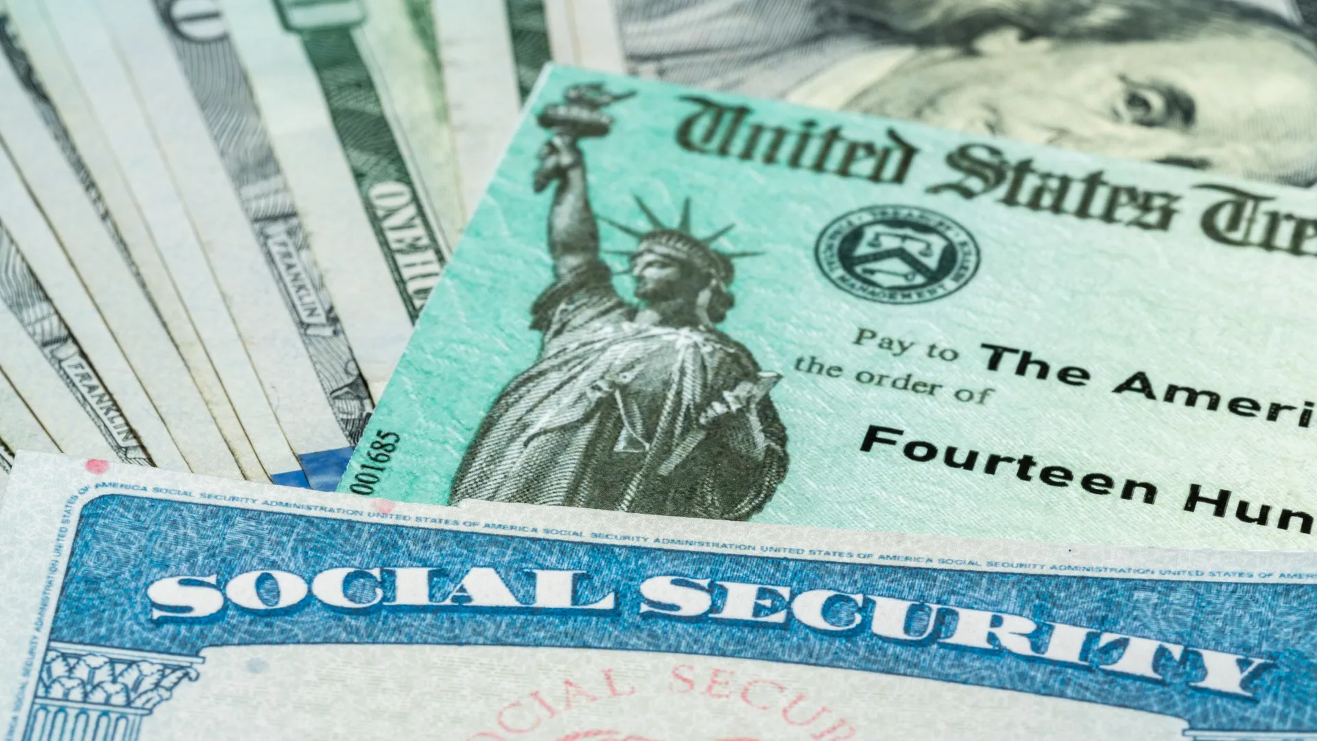 一叠带有美国财政部说明性支票的100美元钞票，以说明2021年美国救援计划法案为退休人员支付社会保障卡。