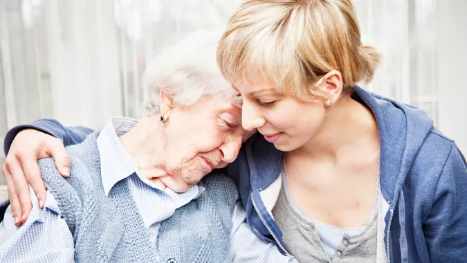 Senior woman, 89 years old, getting comfort by  young home caregiver.