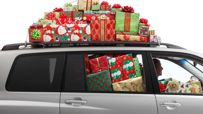 A woman driving a car filled with Christmas presents.